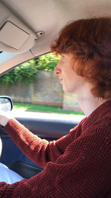 英国18 / 19岁的红发少年坐在车里学习驾驶，集中精力驾驶右手驾驶手动驾驶汽车
